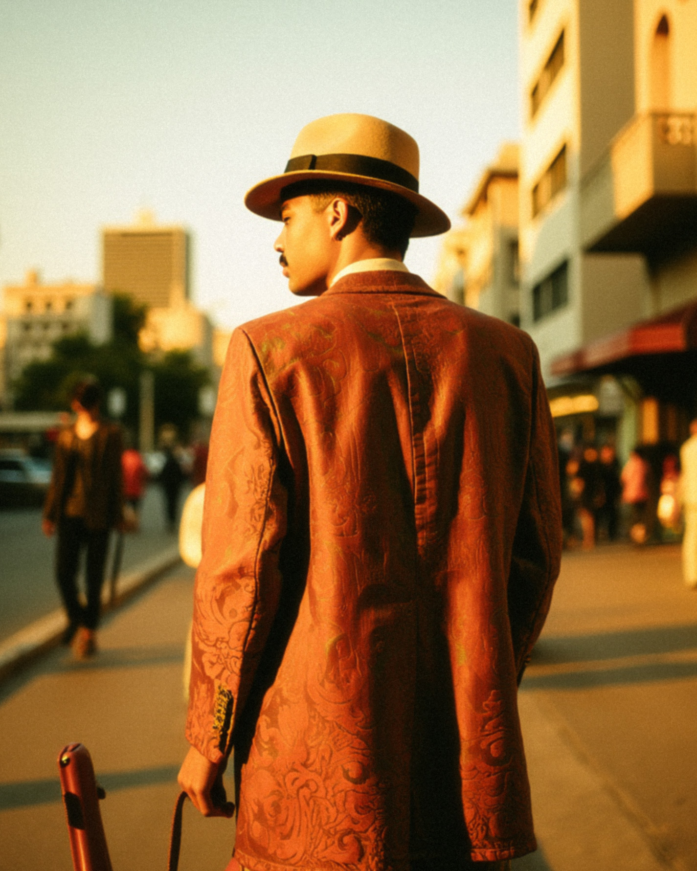 Marco Vincit veste um terno vermelho com padrões sutis, parcialmente aberto, revelando a pele sob uma iluminação dramática. A luz quente e os contrastes criam uma atmosfera intensa e cinematográfica. — Retratos, Marco Vincit